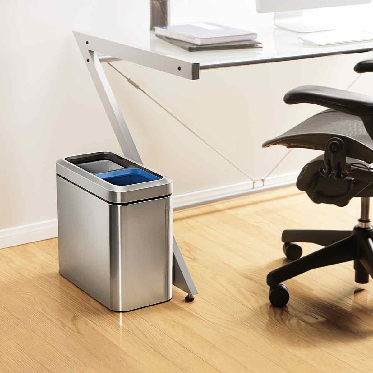 Lifestyle shot of Simplehuman Brushed Stainless Steel 20L Dual Compartment Slim Open Can under an office desk, space-saving recycling.